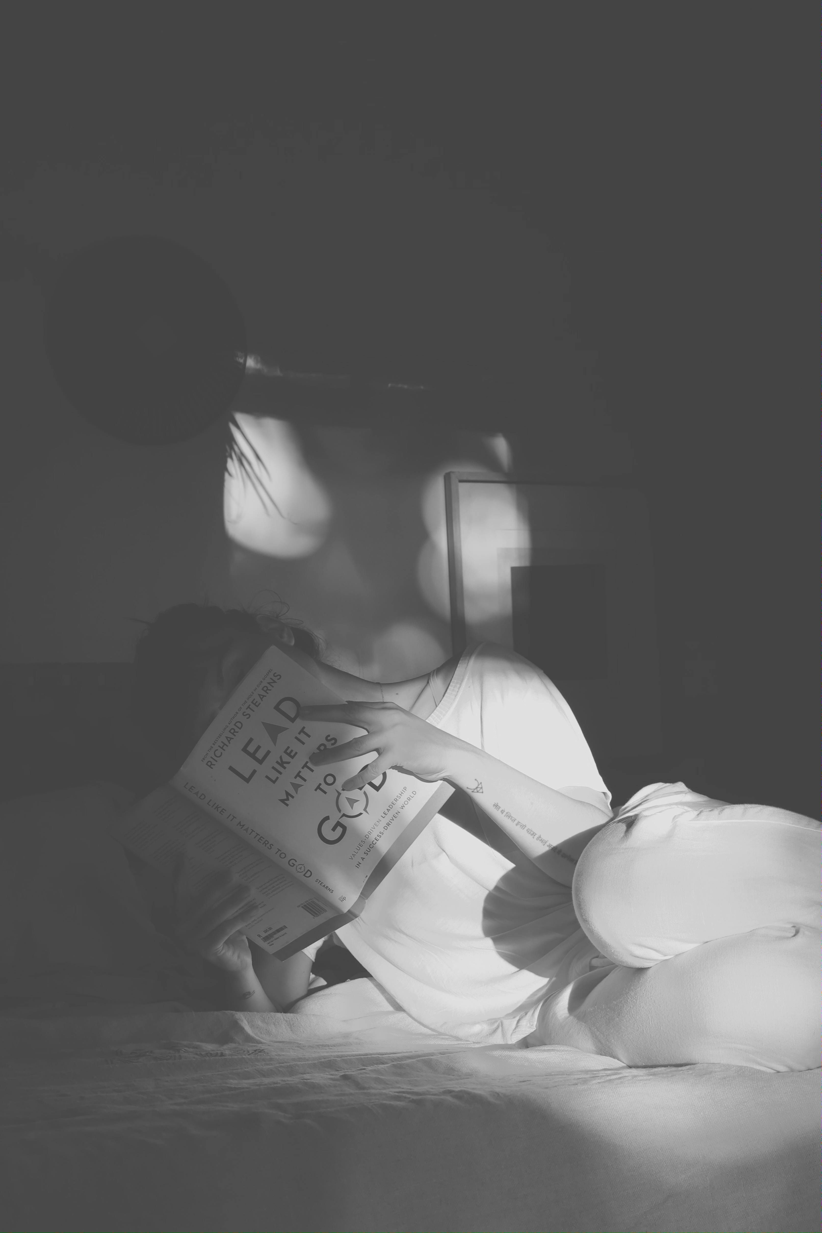 Zadarmo Pokojný okamih s knihou v jemnom popoludňajšom svetle, zachytený monochromaticky. Fotka z fotobanky