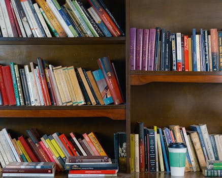 A warm library setting with filled bookshelves and a coffee cup on the table.
