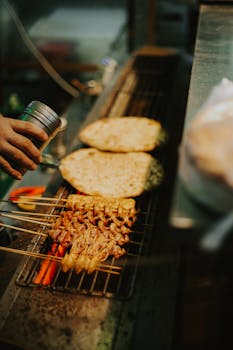 Delicious skewered chicken grilling at a bustling Nanjing night market.