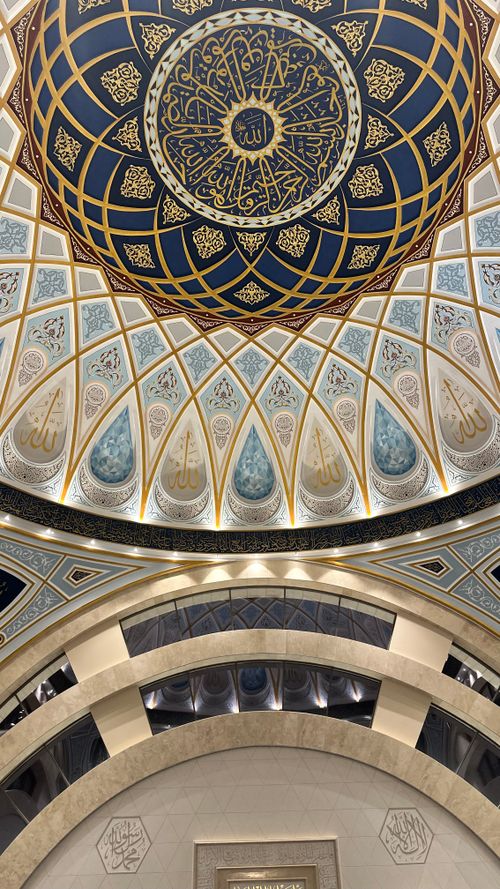 Free A beautifully detailed view of an elaborate mosque ceiling showcasing Islamic art and calligraphy. Stock Photo