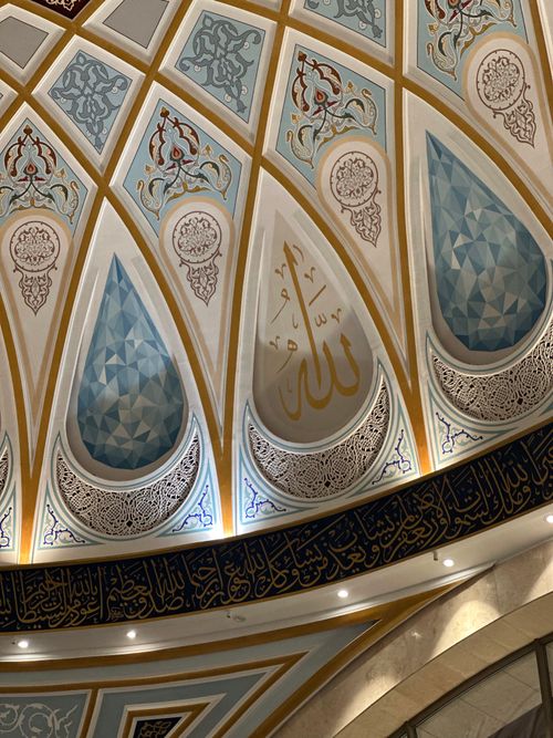 Free A detailed view of ornate Islamic architecture featuring arabesque patterns and calligraphy in a mosque interior. Stock Photo