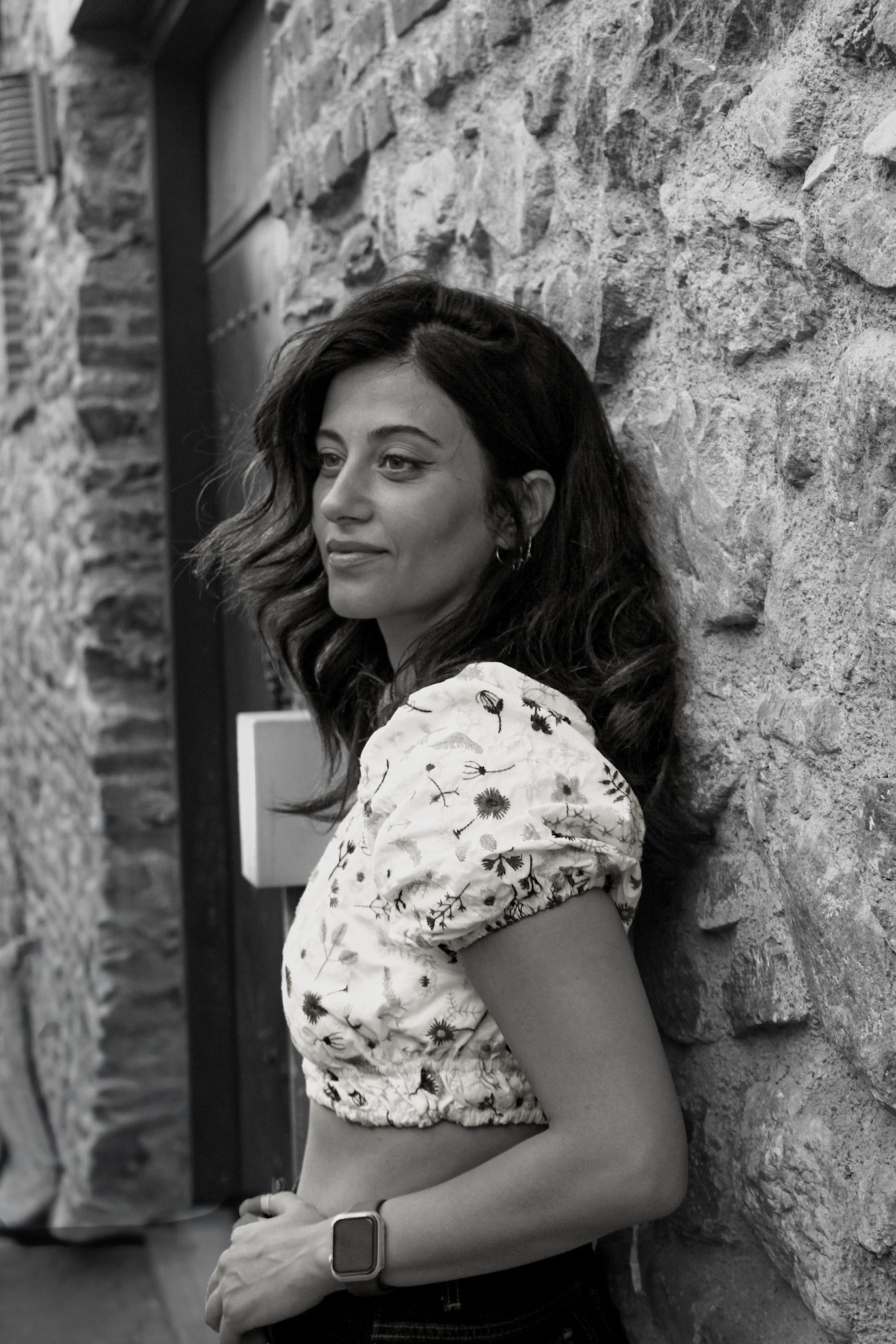 Black and white portrait of a woman leaning against a stone wall in Bursa, Türkiye.
