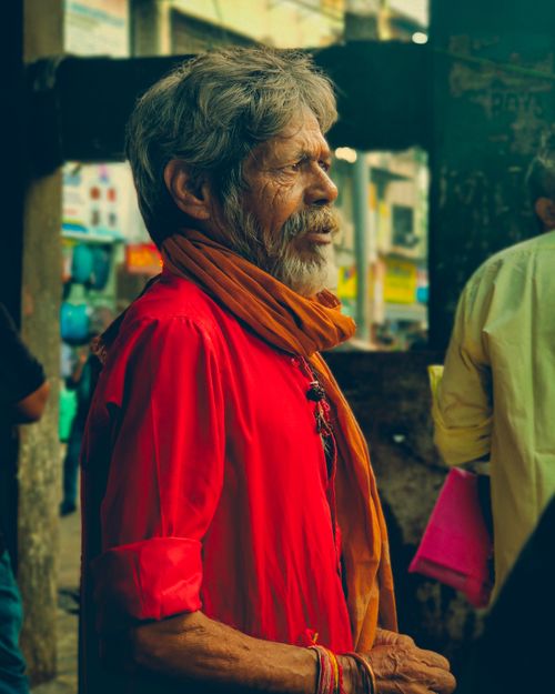 Free An elderly Indian man in vibrant traditional attire stands in Mumbai, capturing candid street life. Stock Photo