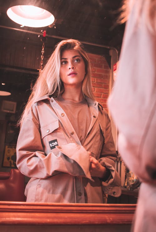 Woman in Brown Coat Standing Near Red Wall