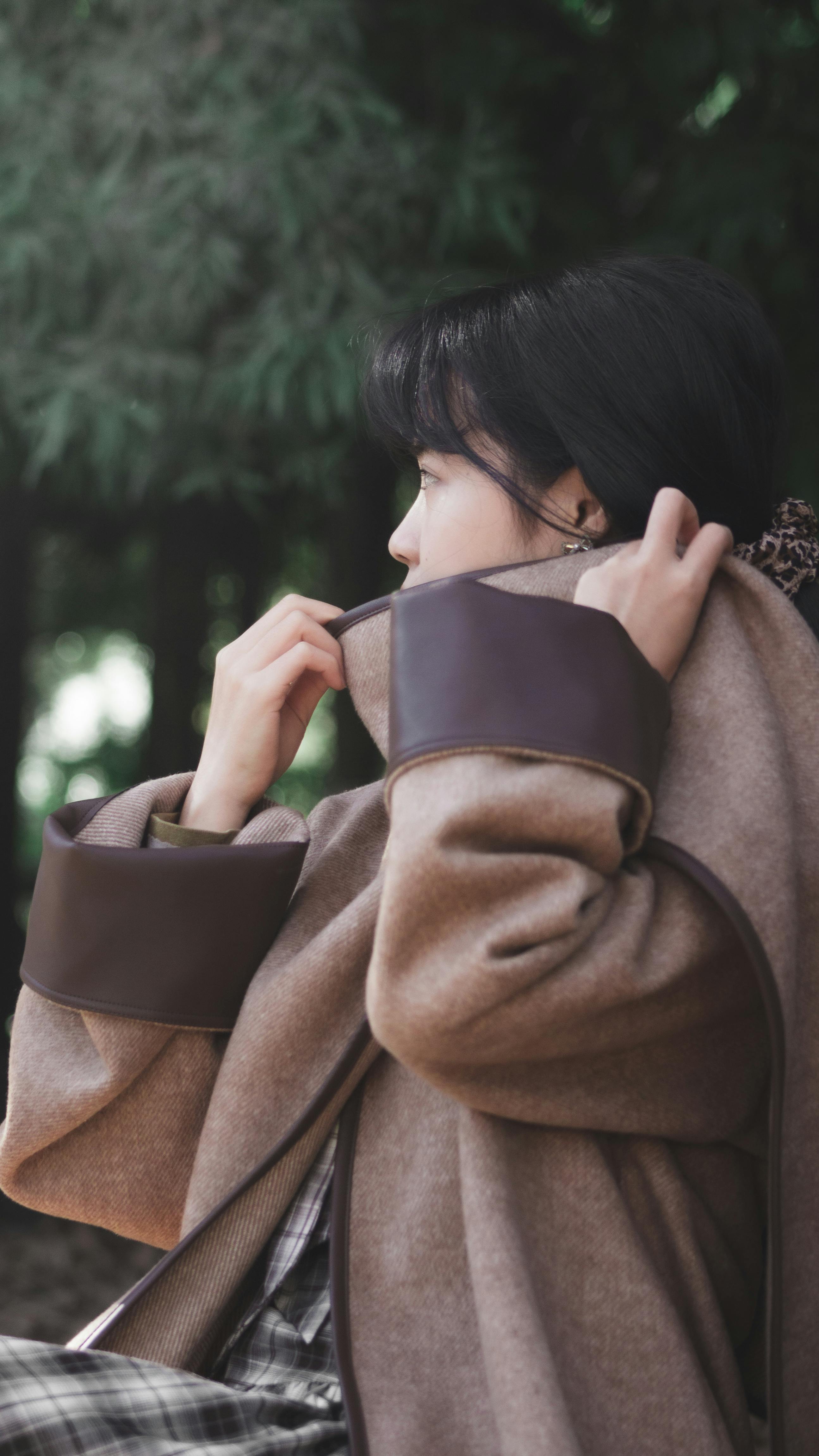 Side profile of a woman in a chic winter coat outdoors, creating a serene and elegant vibe.