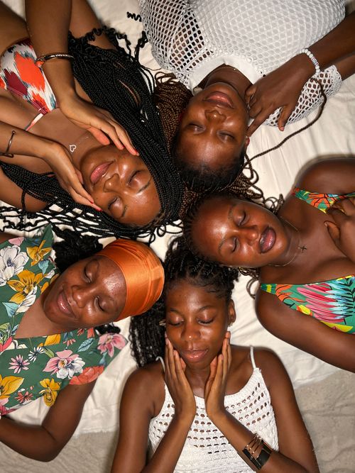 Free Five women lying on a bed, enjoying a relaxing moment together. Stock Photo