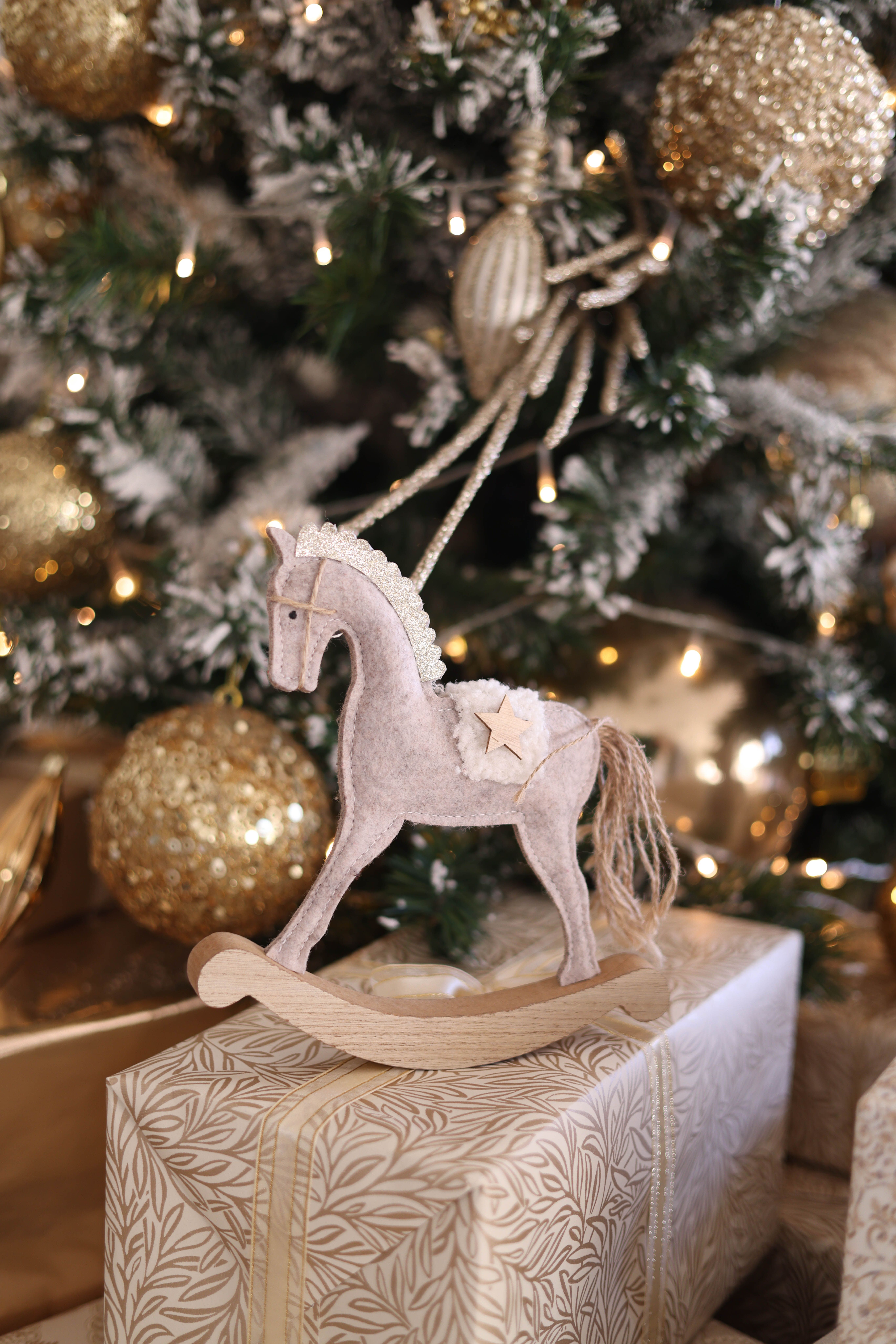 Beautiful Christmas setting with a decorative rocking horse ornament and golden accents.