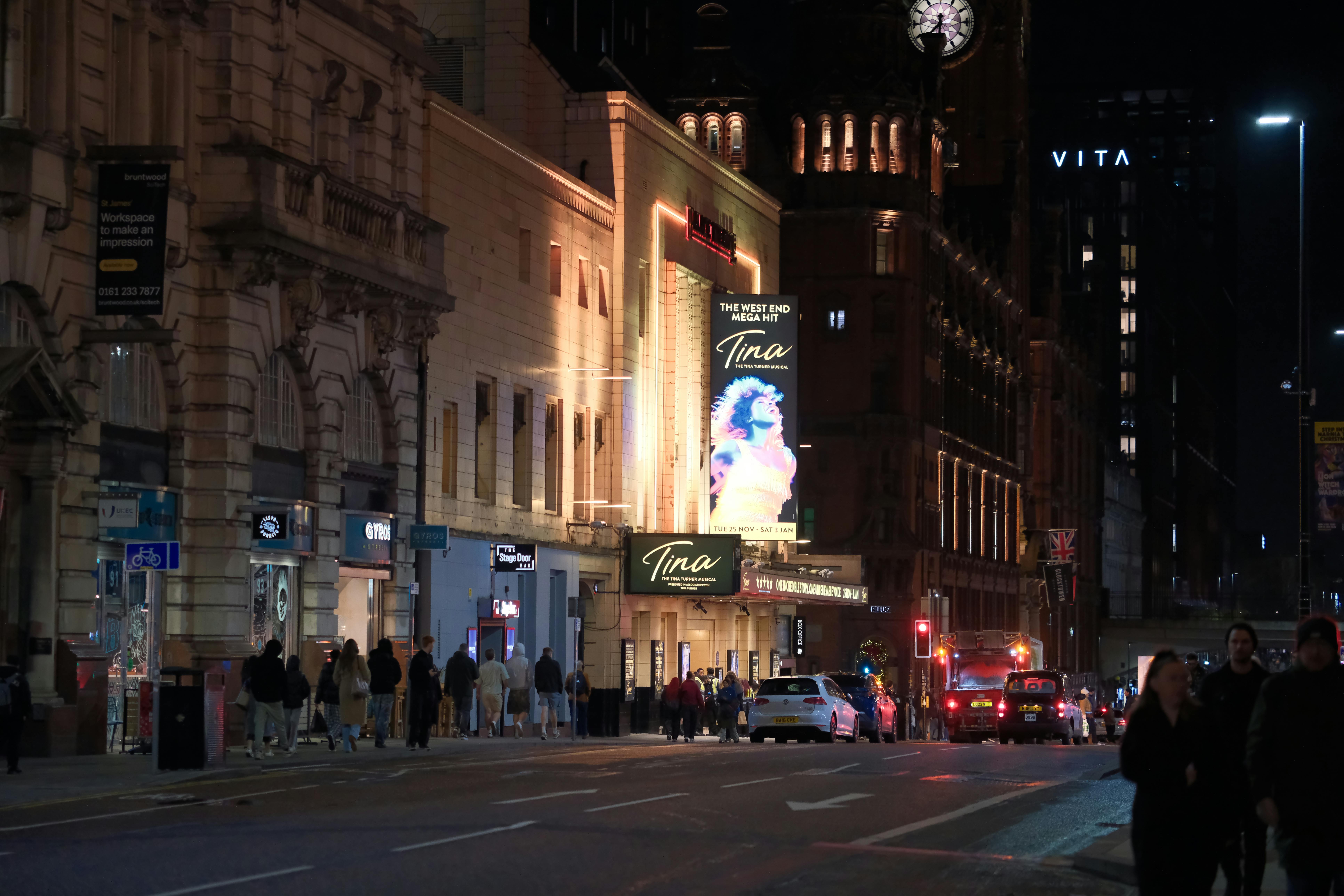 grátis Uma rua movimentada da cidade à noite, com um teatro iluminado e cheio de pedestres. Foto profissional