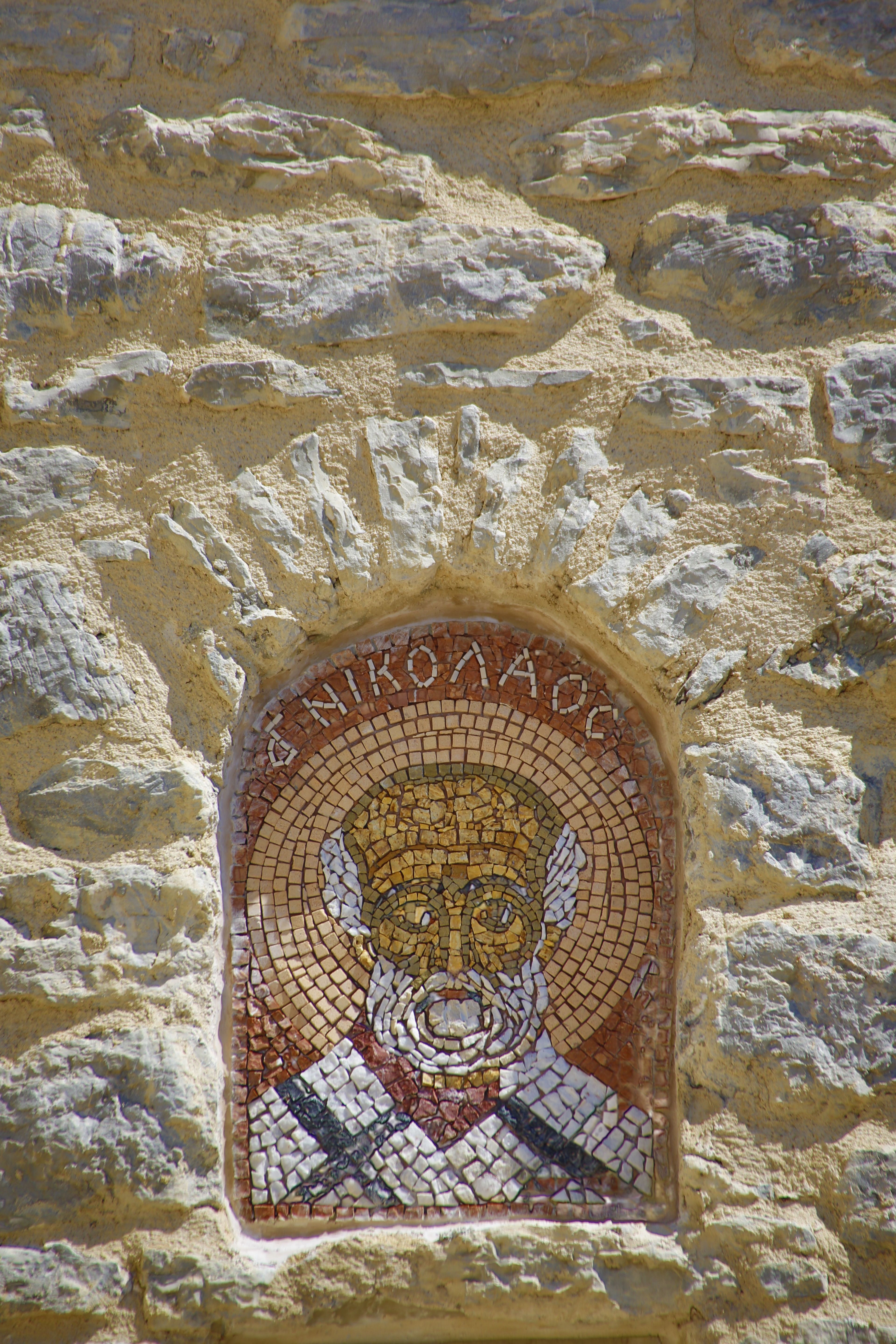 Historic mosaic depiction of St. Nicholas set in an ancient stone wall.