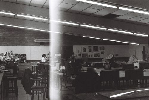 Free Moody black and white image showcasing an empty art classroom with people at desks. Stock Photo