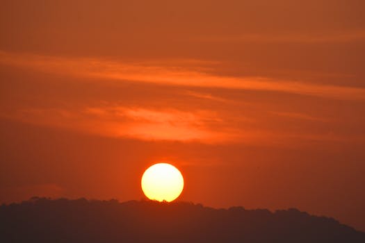A captivating view of the sunrise over the hills in Mumbai, India with a vibrant orange sky.