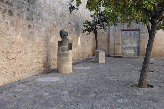 A serene stone plaza featuring a bust and wall art in El Puerto de Santa María, Spain.