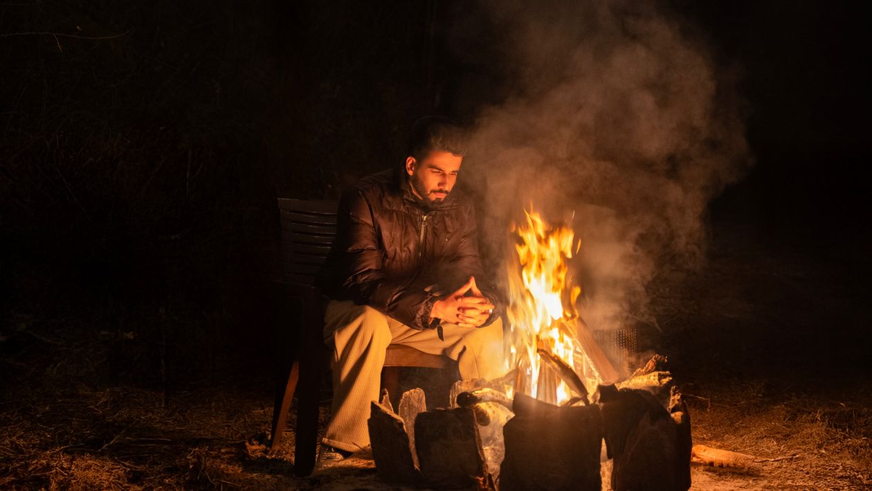 Man Reflecting Near a Campfire at Night · Free Stock Photo
