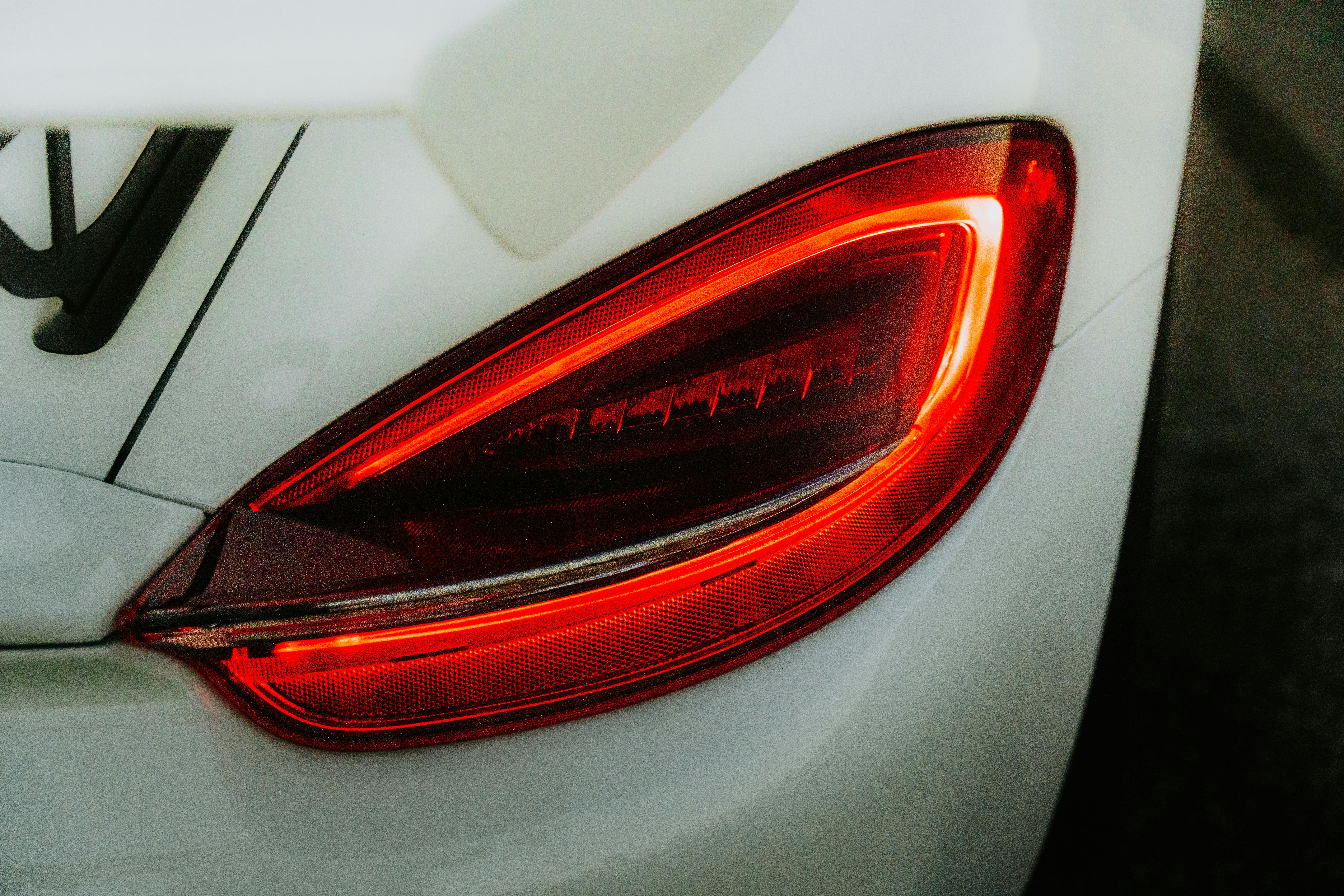Detailed view of car tail light glowing red, captured during daylight.