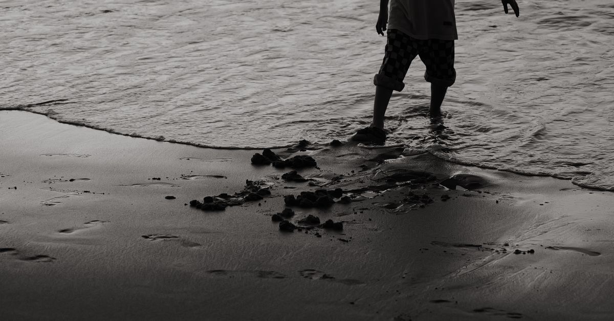 Silhouette of a child playing at the edge of the ocean shore