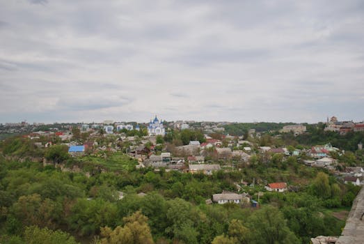 A picturesque aerial view of a Ukrainian town featuring a prominent blue-domed church amidst lush greenery.