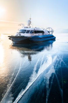 A hovercraft moving over a cracked, frozen lake during a bright winter day. — photo by Dmitriy Ryndin