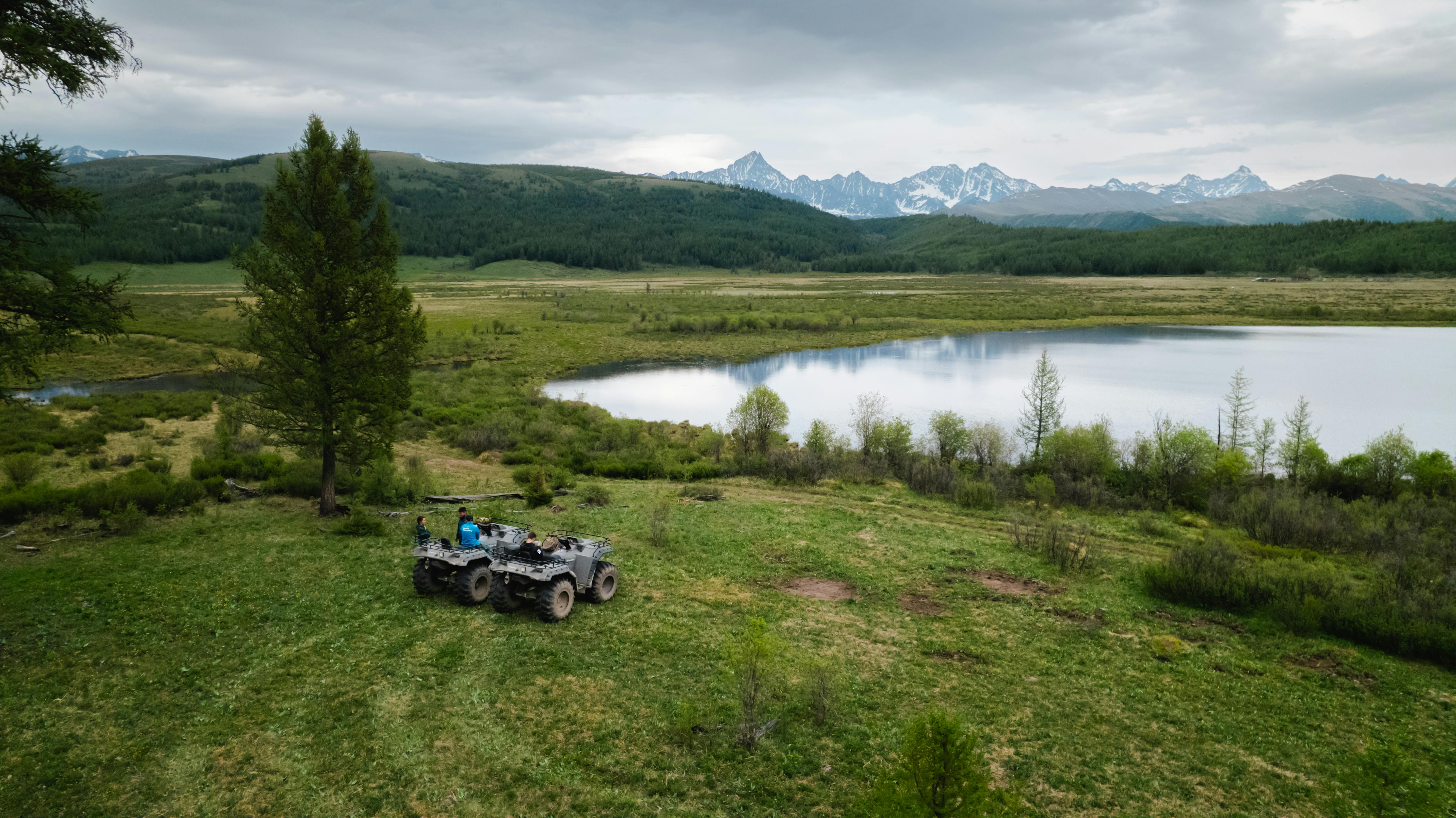 ATV riders exploring a picturesque mountain landscape with a serene lake view.