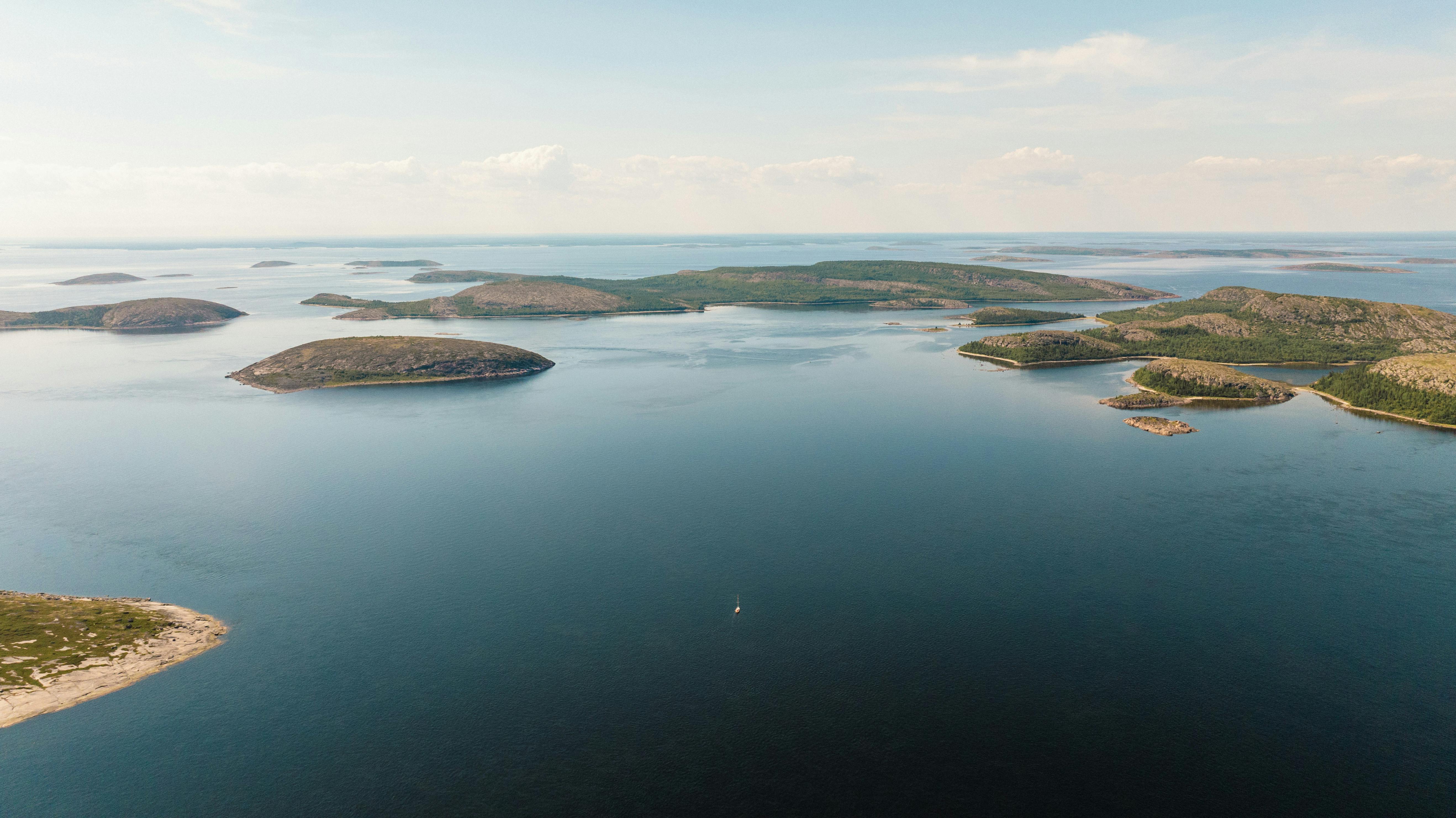 Kornati archipelago at golden hour, Croatia: Emerald waters surrounding rugged limestone islands, soft evening light illuminating ancient olive groves with fishing boats in distance