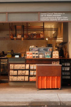 Warm-toned coffee shop counter adorned with supplies and a CCTV notice above.
