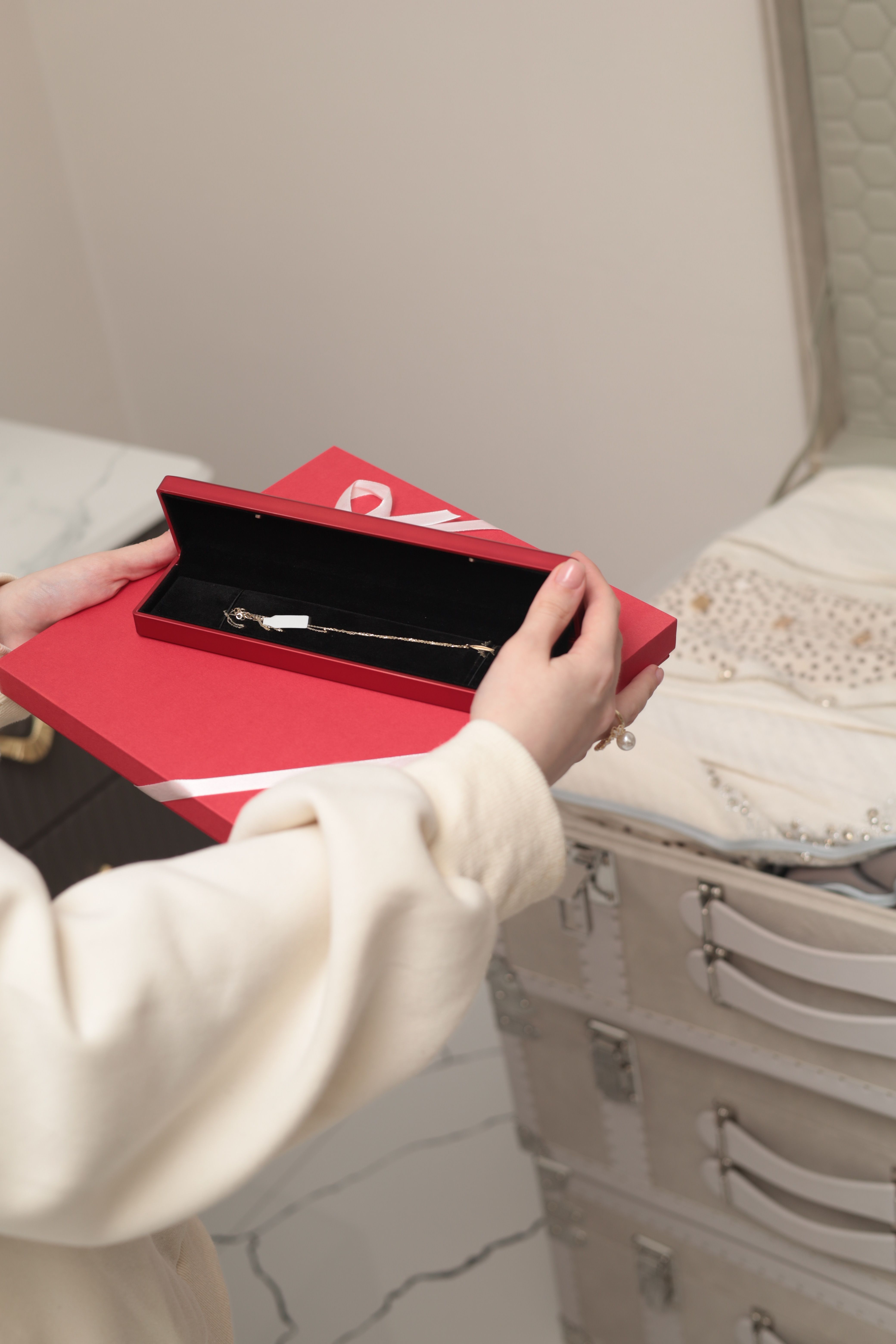 Woman holding a red gift box with a bracelet inside. Perfect for gifting occasions.
