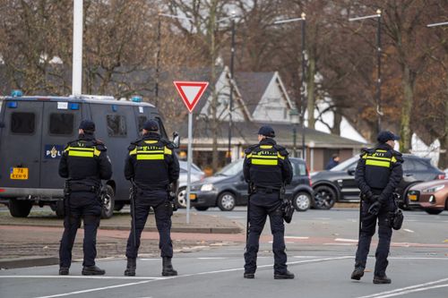 Free Four police officers stand vigilant on city street near patrol van, ensuring public safety. Stock Photo