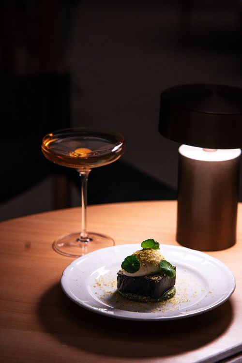 Free Chic dining scene in Tokyo featuring gourmet cuisine and cocktails under moody lighting. Stock Photo