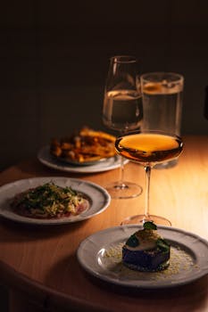 Tastefully arranged gourmet dishes and drinks in a dimly-lit Tokyo restaurant setting.