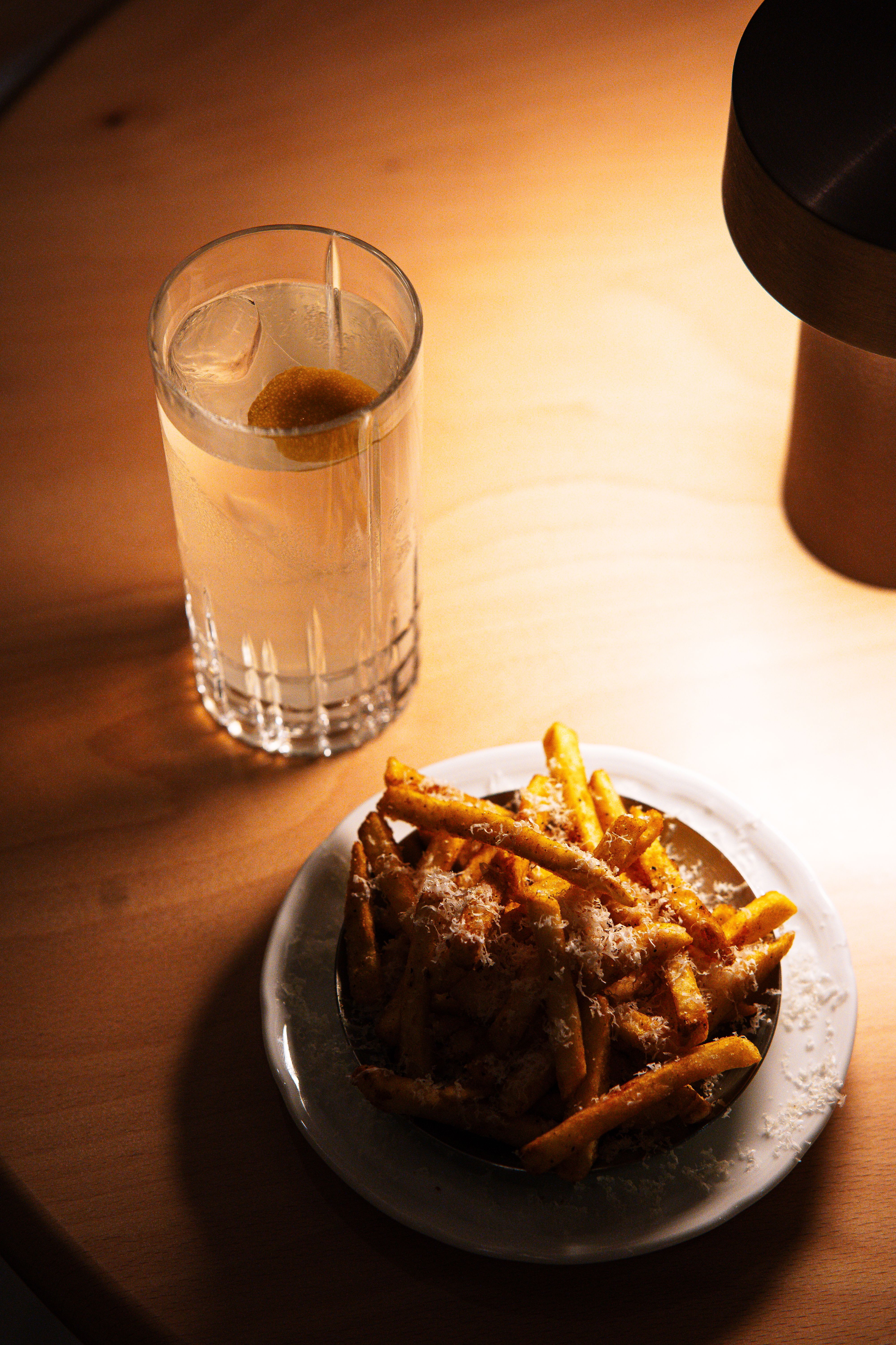 Warm setting with a cocktail and parmesan-dusted fries, perfect for a relaxed dining atmosphere.