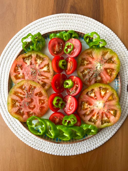 Free Colorful sliced tomatoes and green peppers on a plate, healthy appetizer. Stock Photo