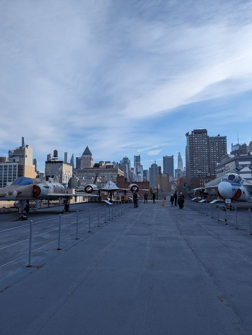 Free Aircraft lined up on a flight deck with a cityscape in the background, showcasing urban aviation. Stock Photo