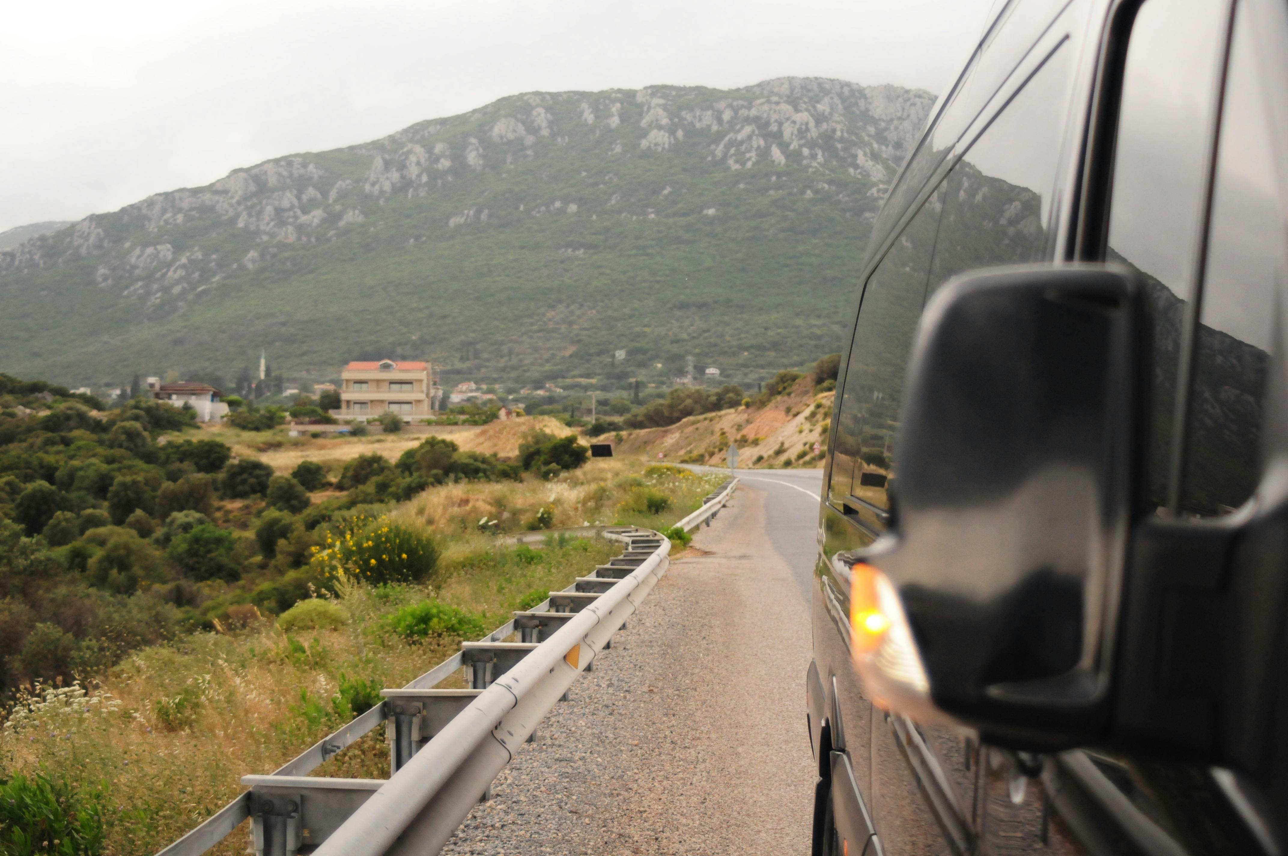 A van reflects a scenic mountain road, capturing natural beauty and travel vibes.