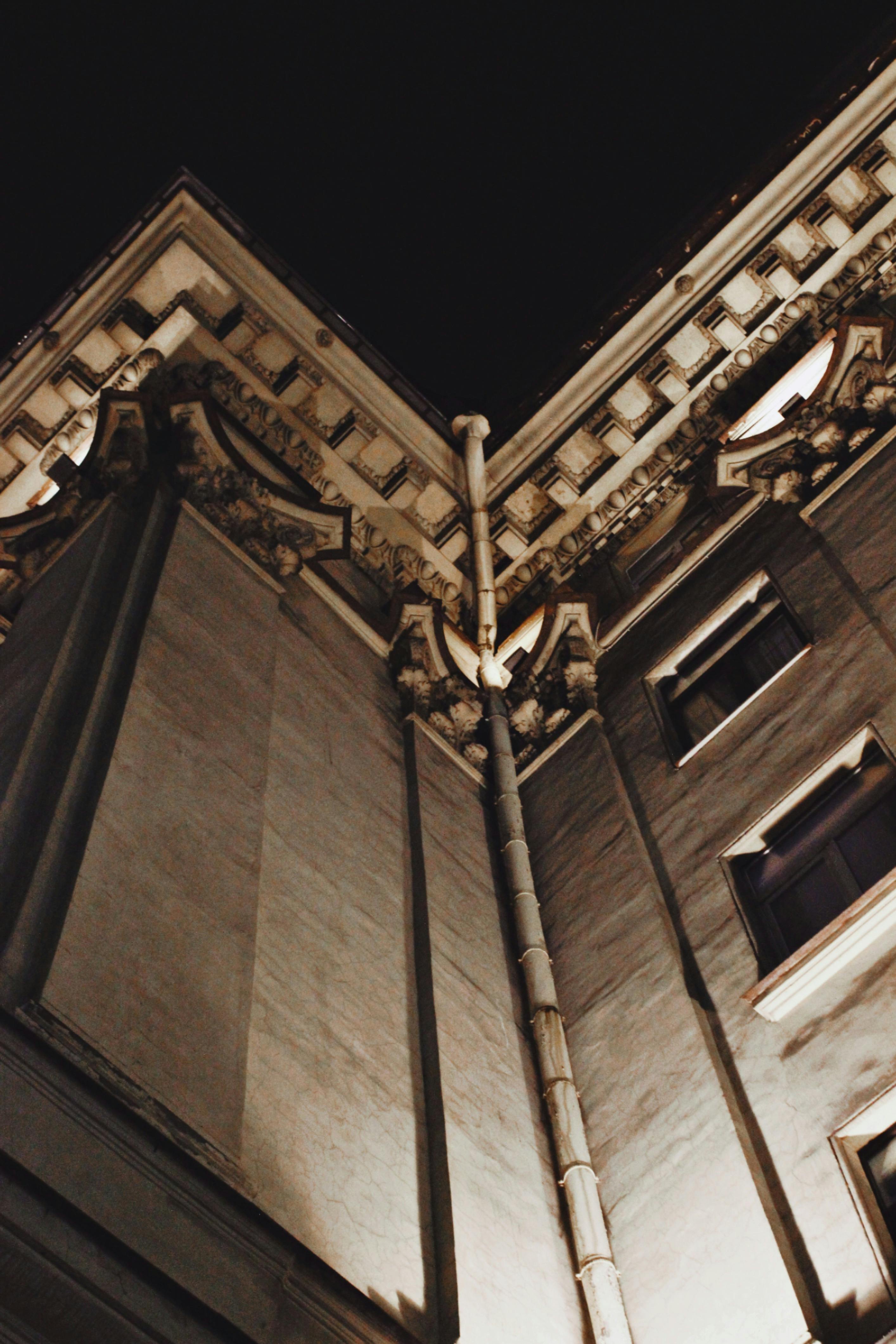 Bezpłatne Widok z dołu na zabytkowy budynek nocą, ukazujący misterne detale architektoniczne. Zdjęcie z galerii