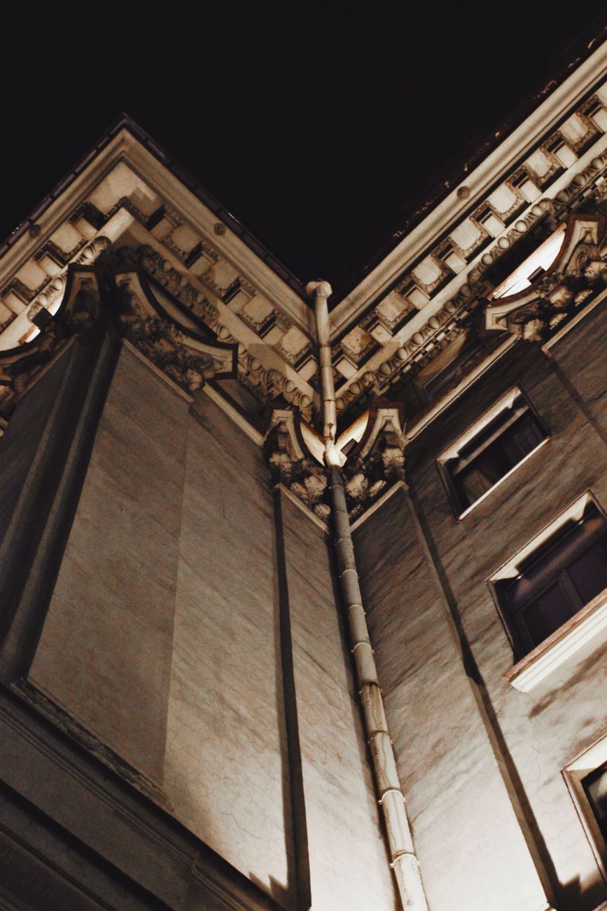 A low-angle view of a historic building at night, showcasing intricate architectural details.