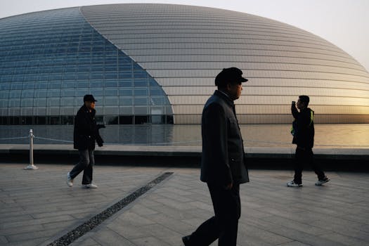 Persone che camminano davanti al Centro nazionale per le arti dello spettacolo al tramonto, Pechino.