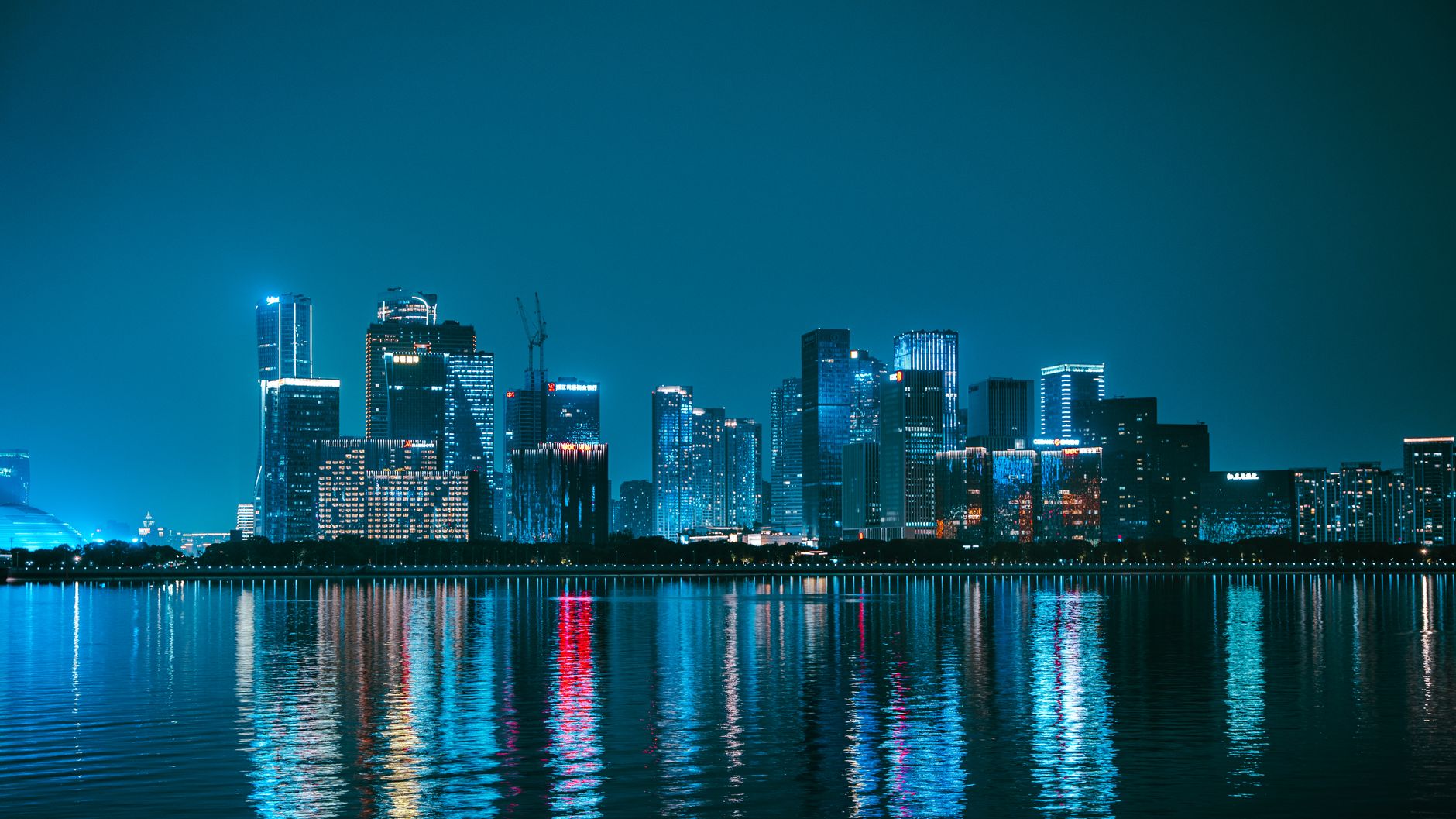 Explore the mesmerizing night skyline of Hangzhou, China, with vibrant reflections on the Qiantang River.