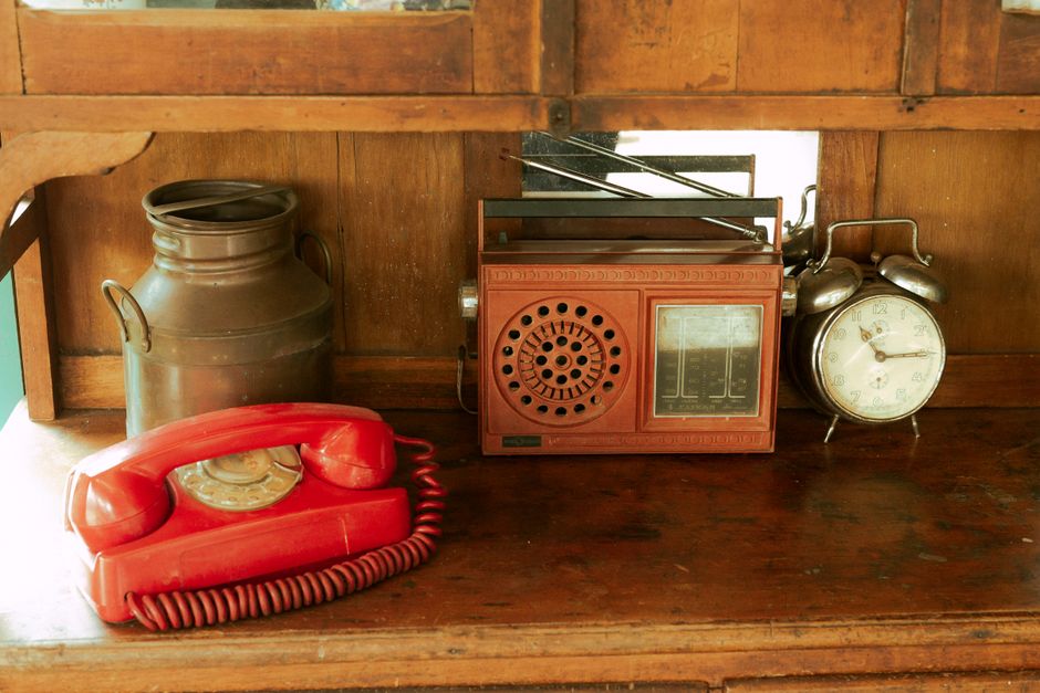 Vintage Scene with Red Rotary Phone, Old Radio, and Antique Clock on Wooden Shelf, representing complex financial systems.