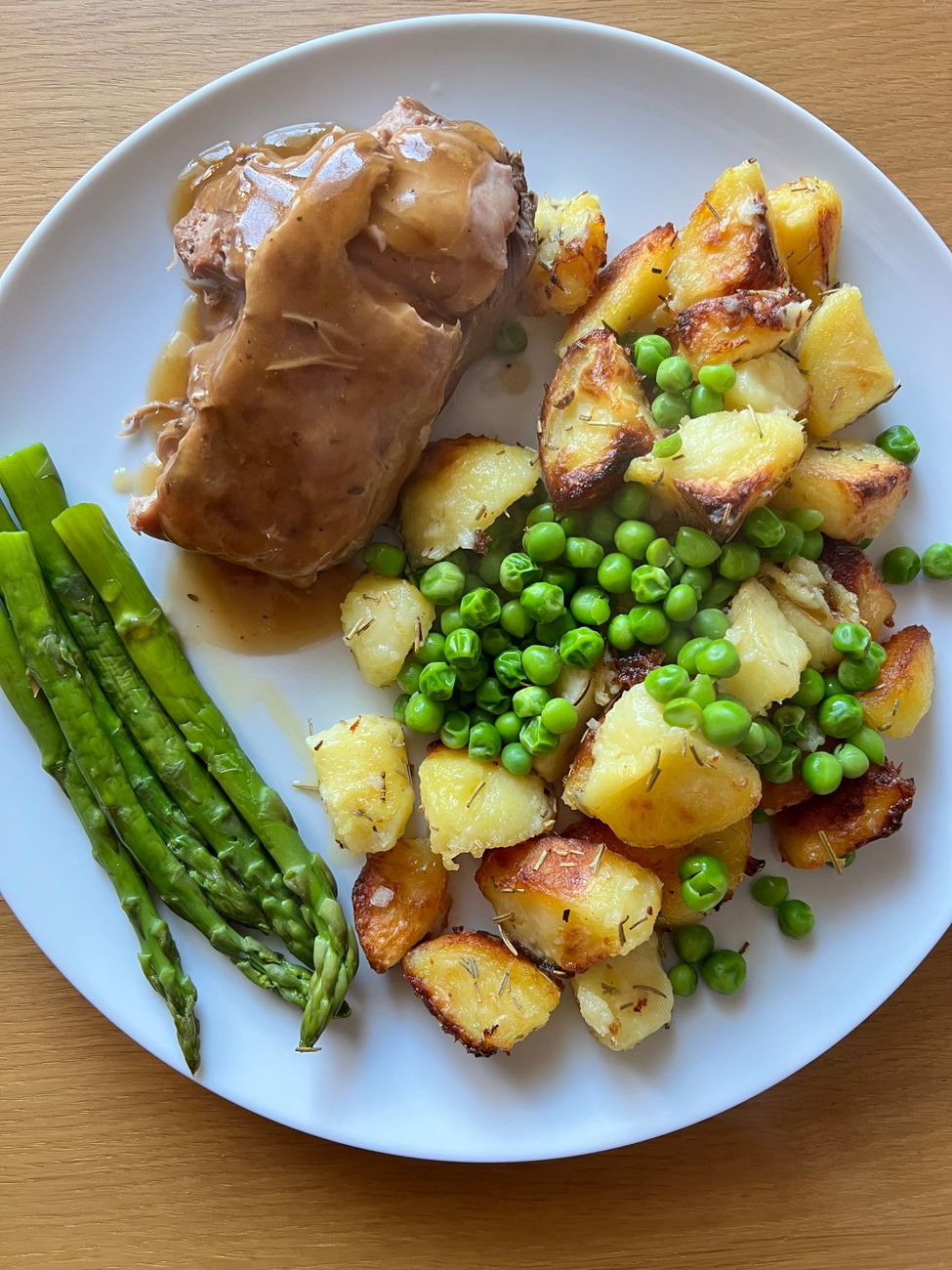 Golden-brown pork chops nestled in thick, mahogany gravy dotted with diced onions, celery, and bell peppers, finished with fresh green onions on a white plate