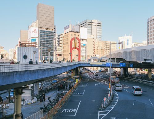 Free Busy urban street with elevated walkway and people walking, reflecting modern city life. Stock Photo