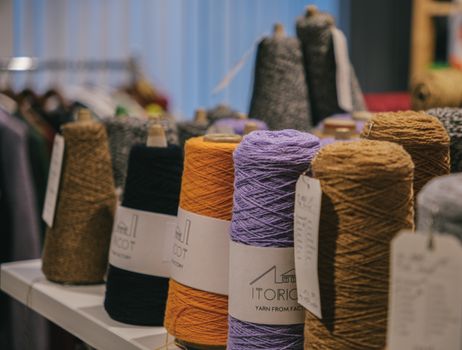 Vibrant yarn spools stacked on a table in a cozy yarn shop, showcasing diversity in colors and textures.