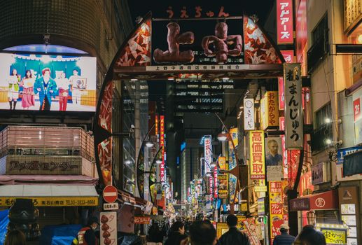 Lively evening street market in Ueno, Tokyo, filled with colorful signs and bustling crowds.
