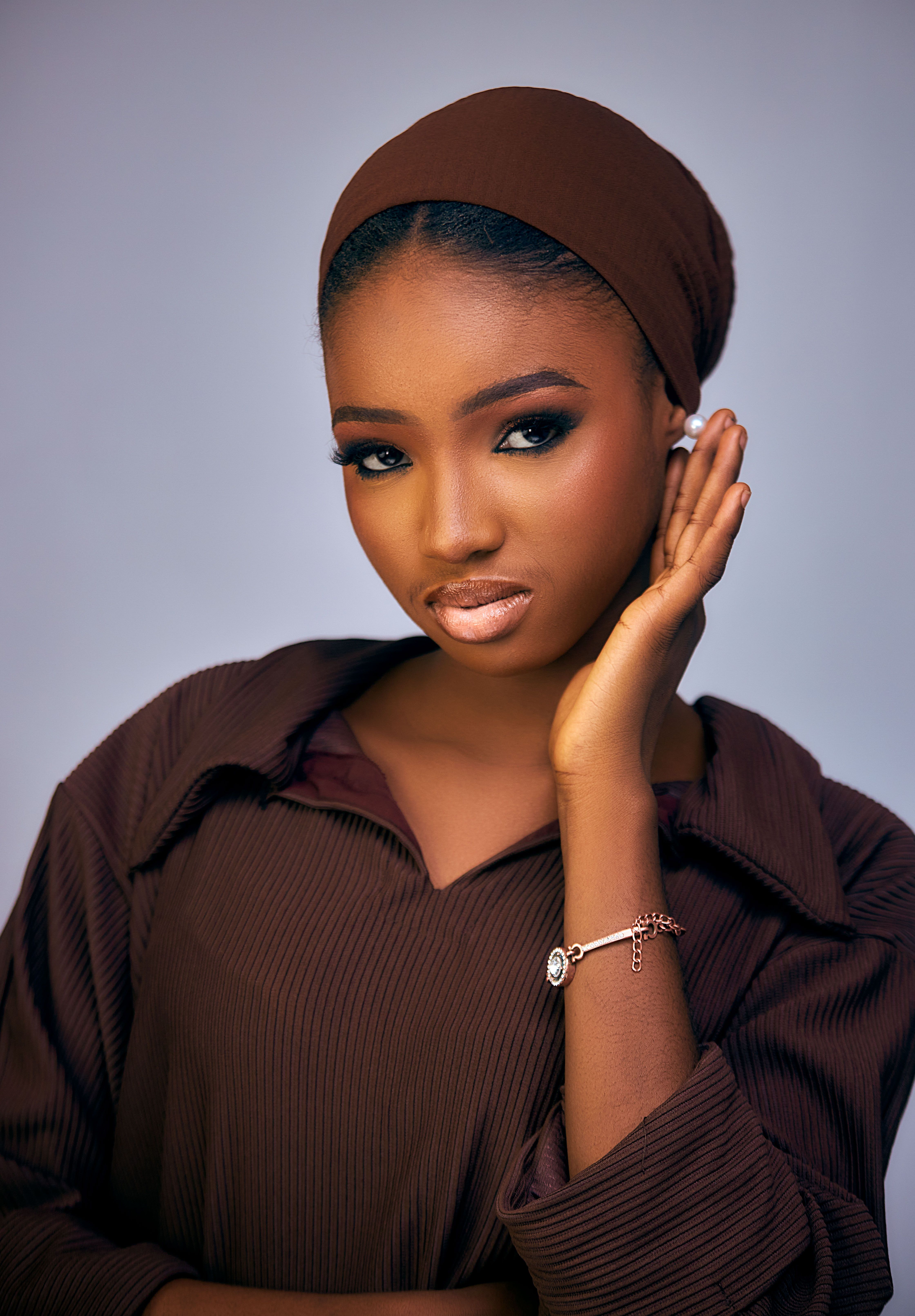 Portrait of a young woman in brown attire, displaying elegance and poise.