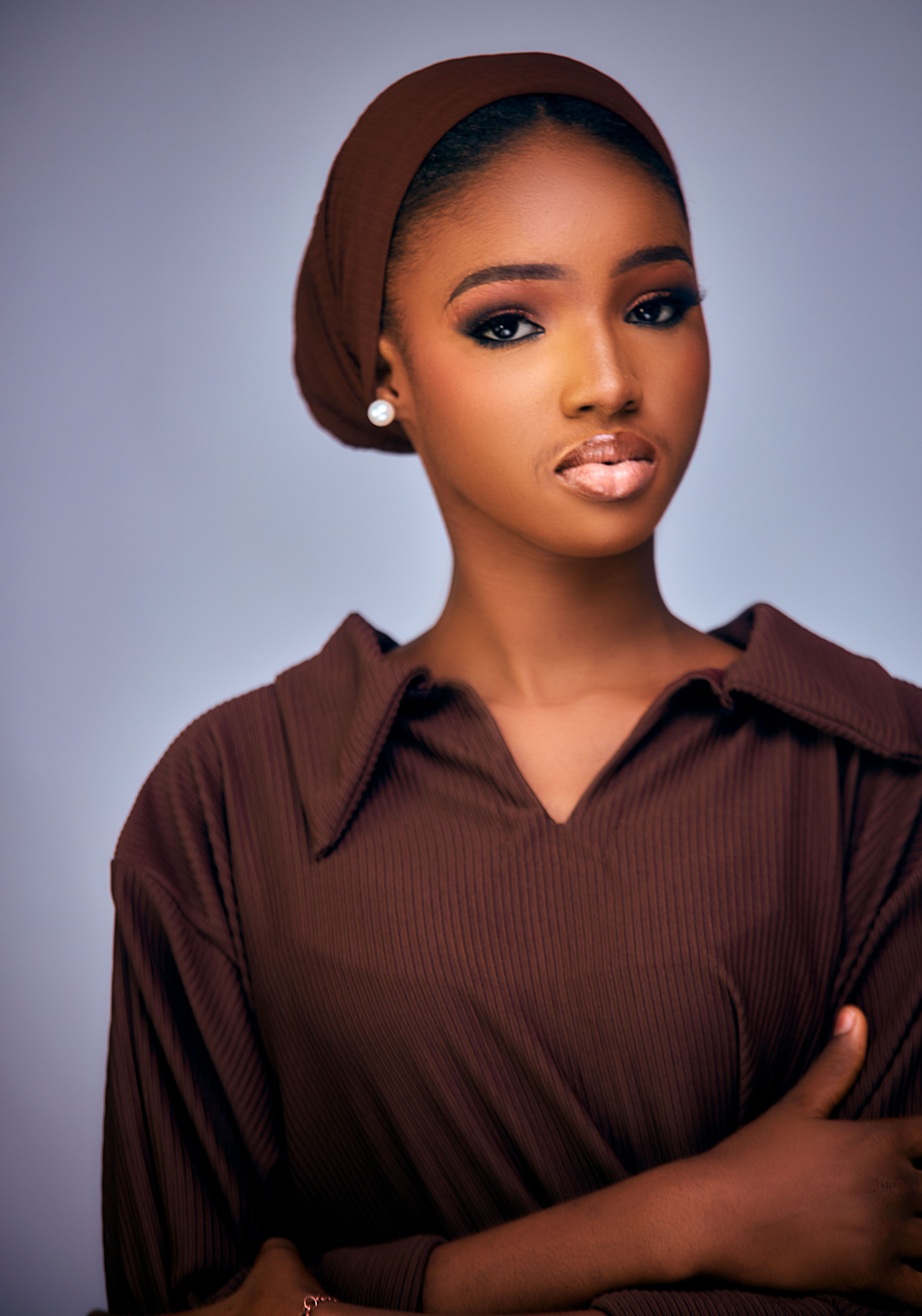 A striking portrait of a young woman wearing a brown hijab, exuding elegance and confidence.