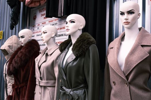 Row of mannequins displaying fashionable winter coats outside a shop.