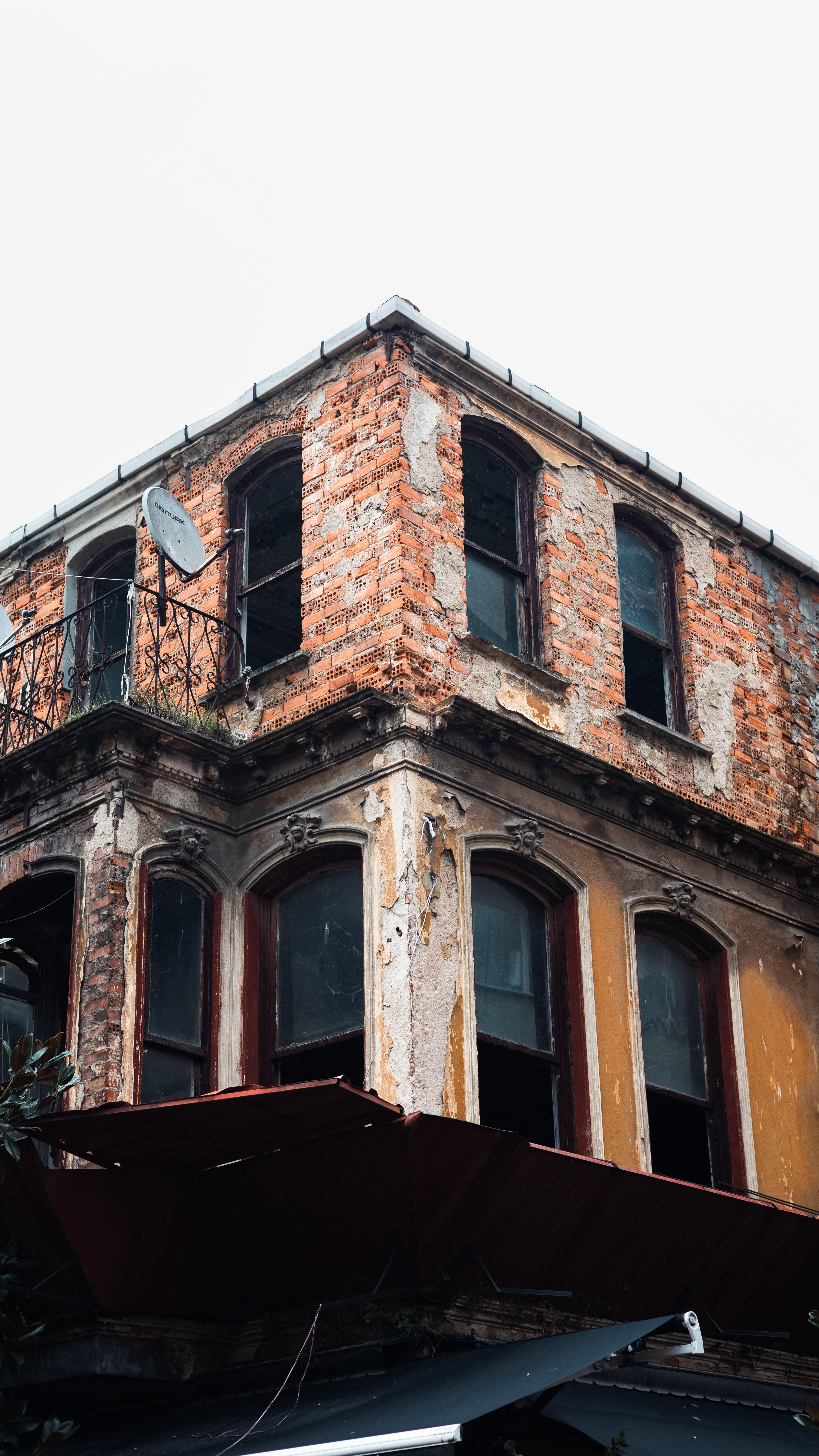 A weathered, two-story abandoned building with exposed brick and old architecture in an urban setting.