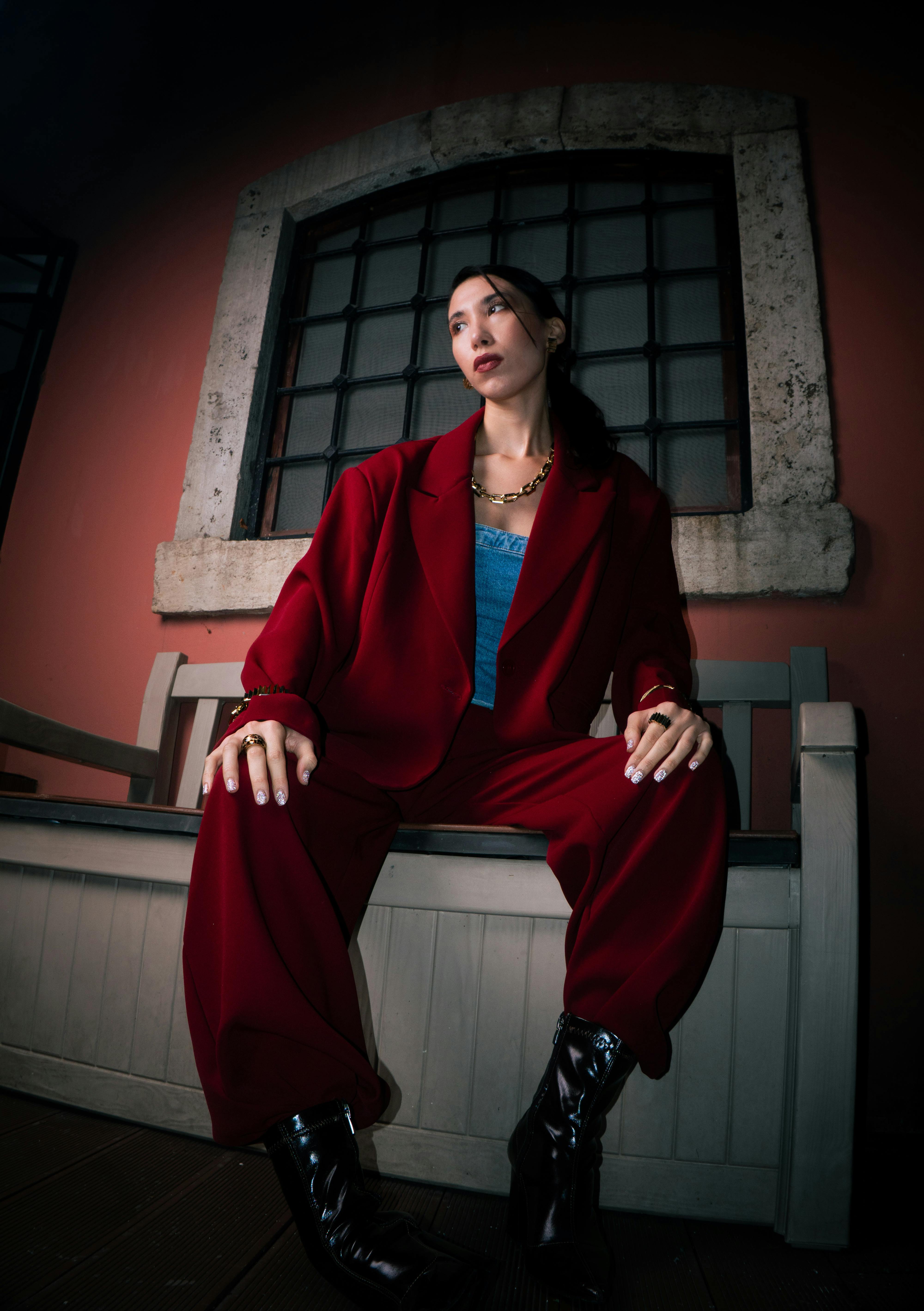 Gratis Mujer elegante con un traje rojo posando en un interior con una iluminación dramática. Foto de stock