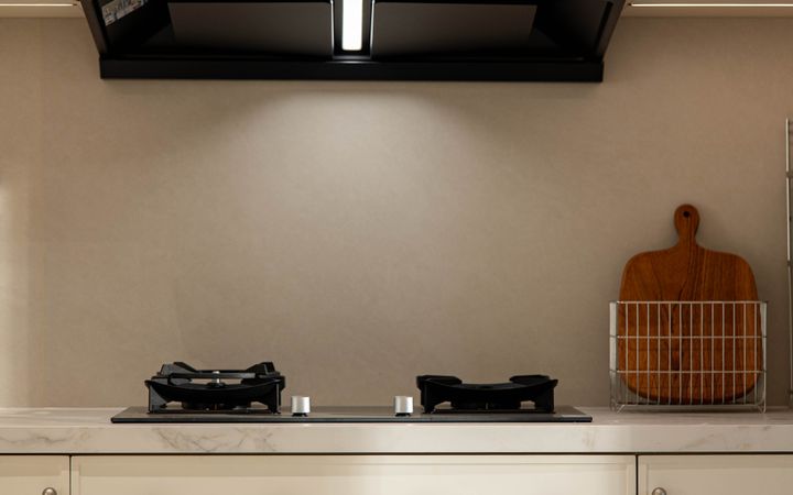 Clean and modern kitchen design with stovetop and chopping board.
