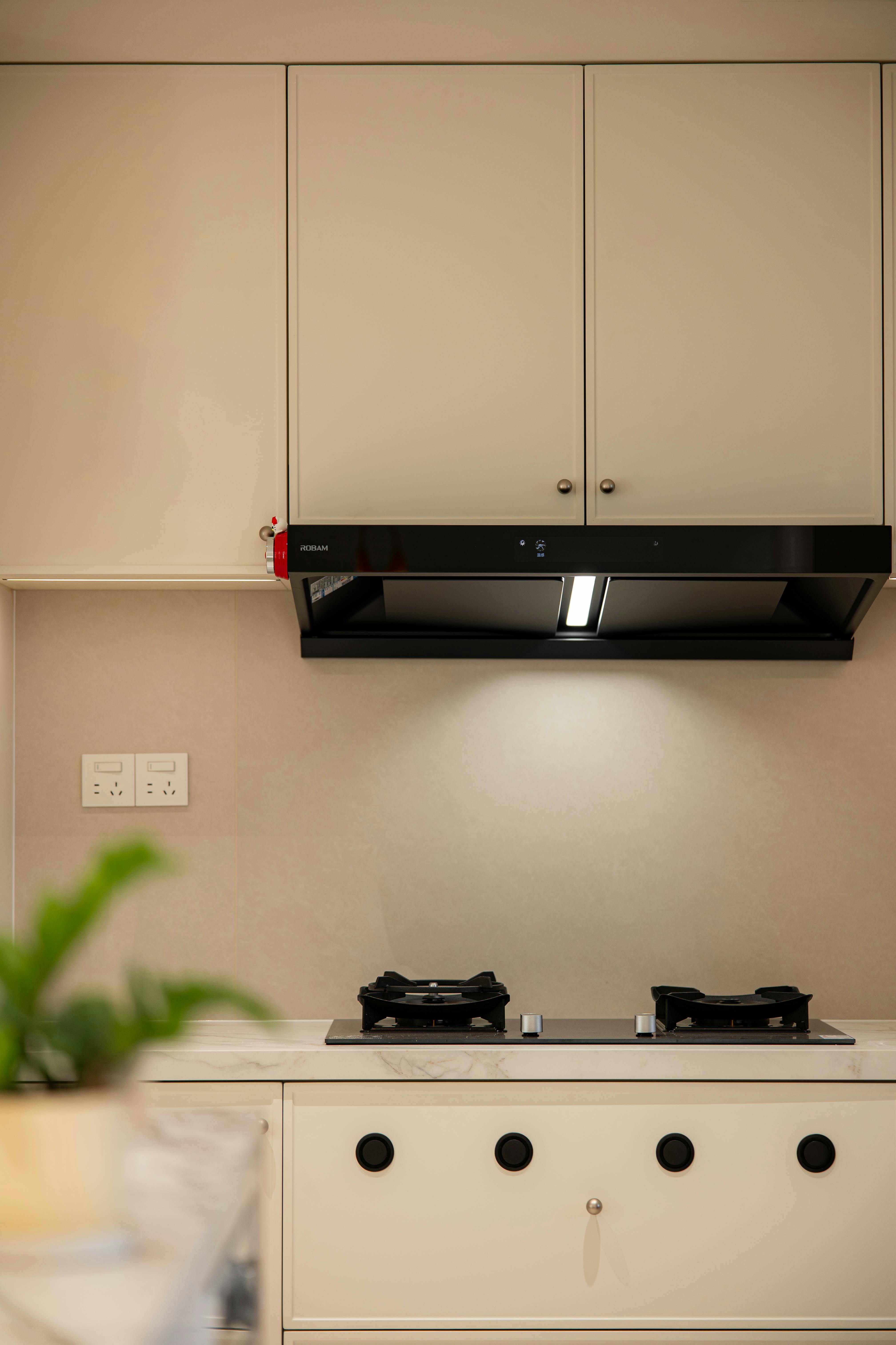 A contemporary kitchen with a sleek stove and black ventilation hood.