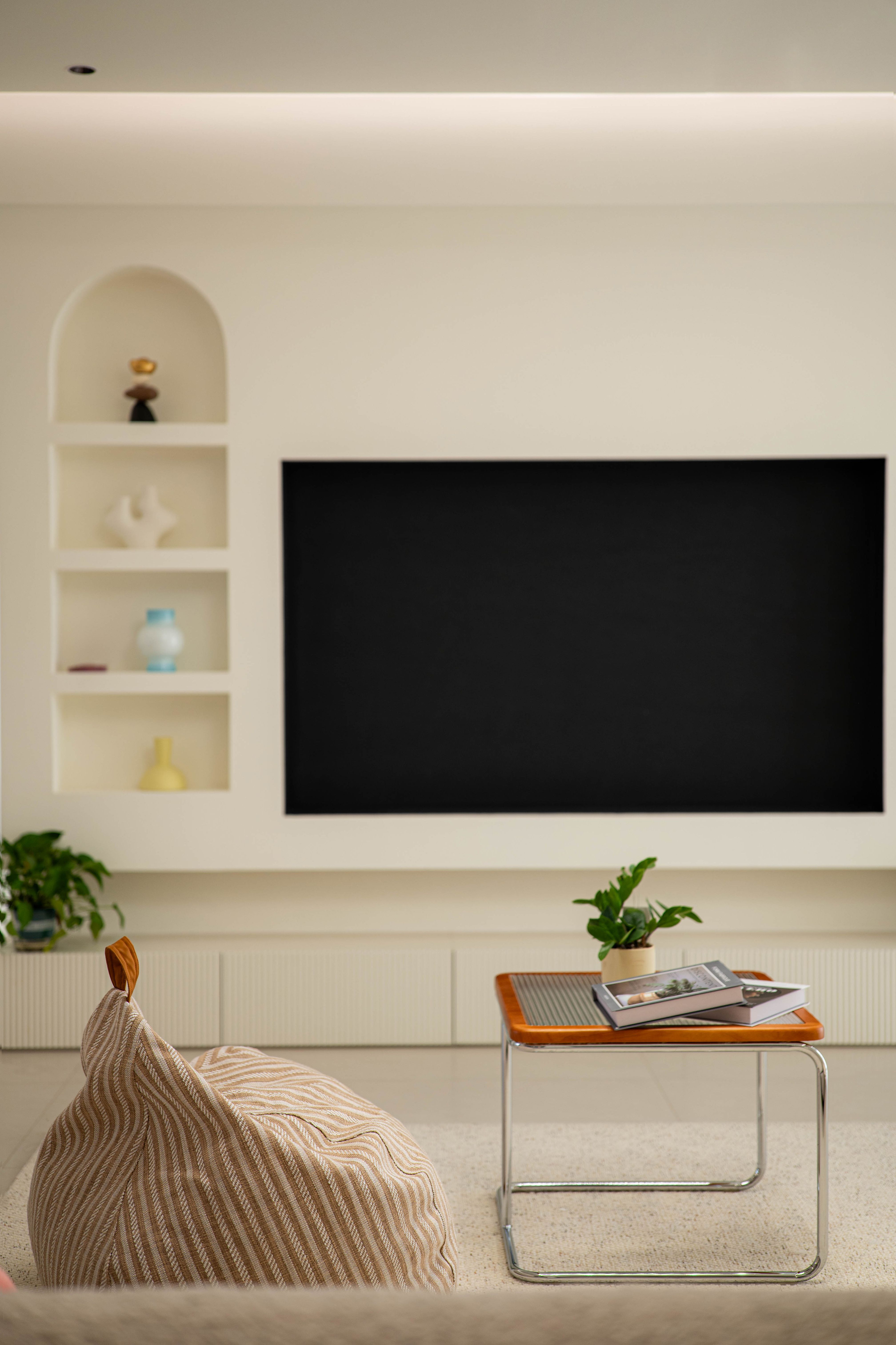 Bright modern living room with minimalist decor, featuring a TV and cozy seating area.