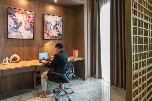 Cozy home office with a man working on a laptop in Jakarta apartment.